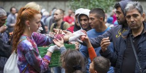 A helper distributes fruit to migrants in front of the State Office for Health and Social Affairs (LaGeSo), in Berlin