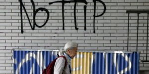 Pedestrian walks past graffiti that reads, "No TTIP", in Brussels, Belgium